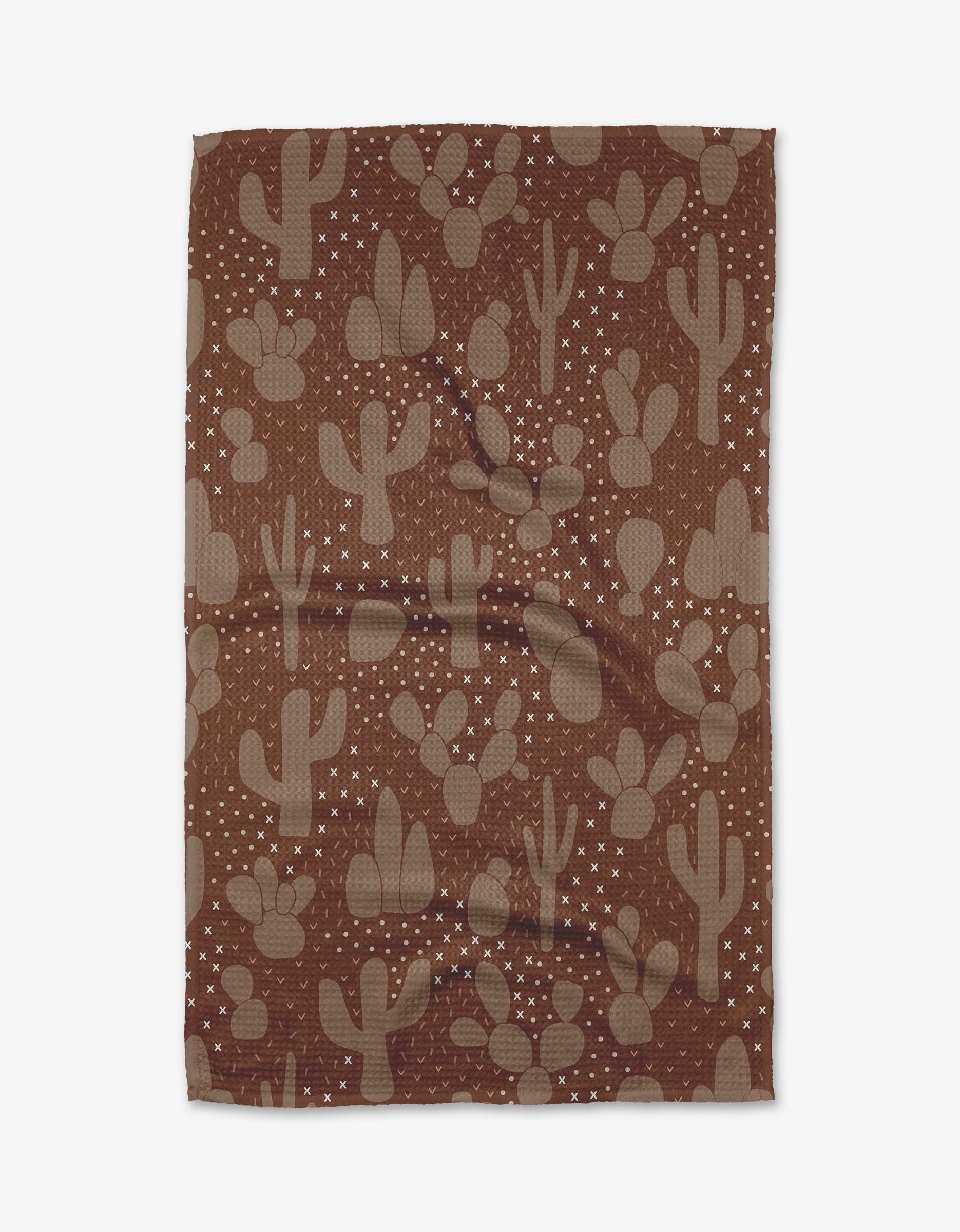 The Desert Night tea towel by Rosa Kichline features Geoweave™ fabric in brown with beige cactus silhouettes and white stars, displayed flat with gentle wrinkles.