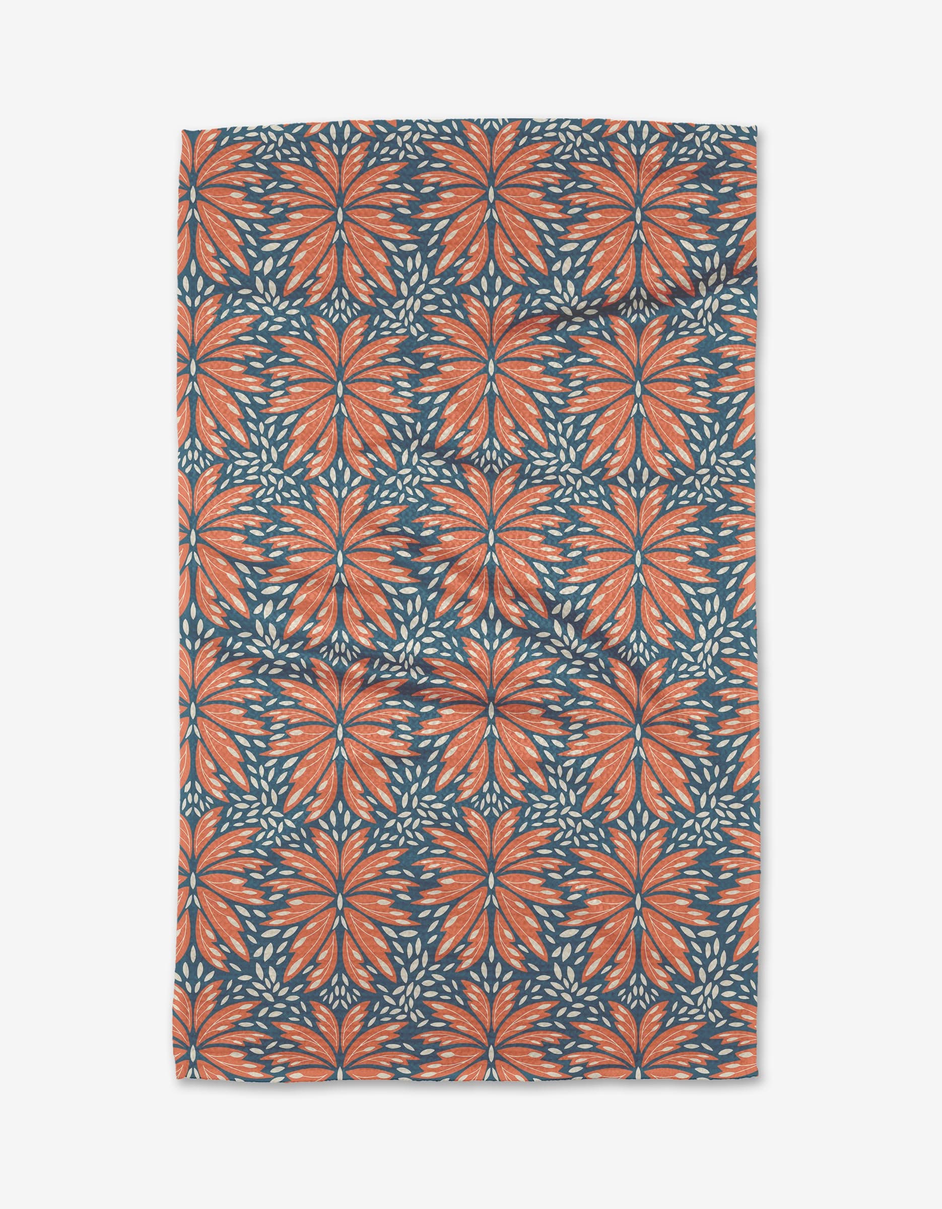 The Dew Drops tea towel by Rebecca Woolbright is made from Geoweave fabric and showcases a repeating orange and blue floral pattern with stylized leaves and petals on a dark blue background.