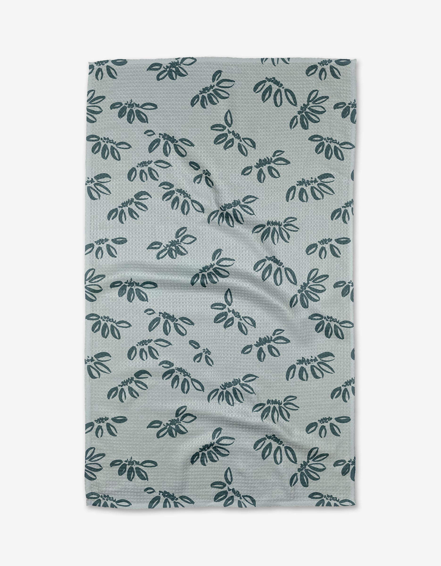 The Discovery Tea Towel by Toboggan Avenue is light gray and made from recycled Geoweave™ fabric, featuring a repeated dark blue leafy branch pattern. Shown flat with visible wrinkles.