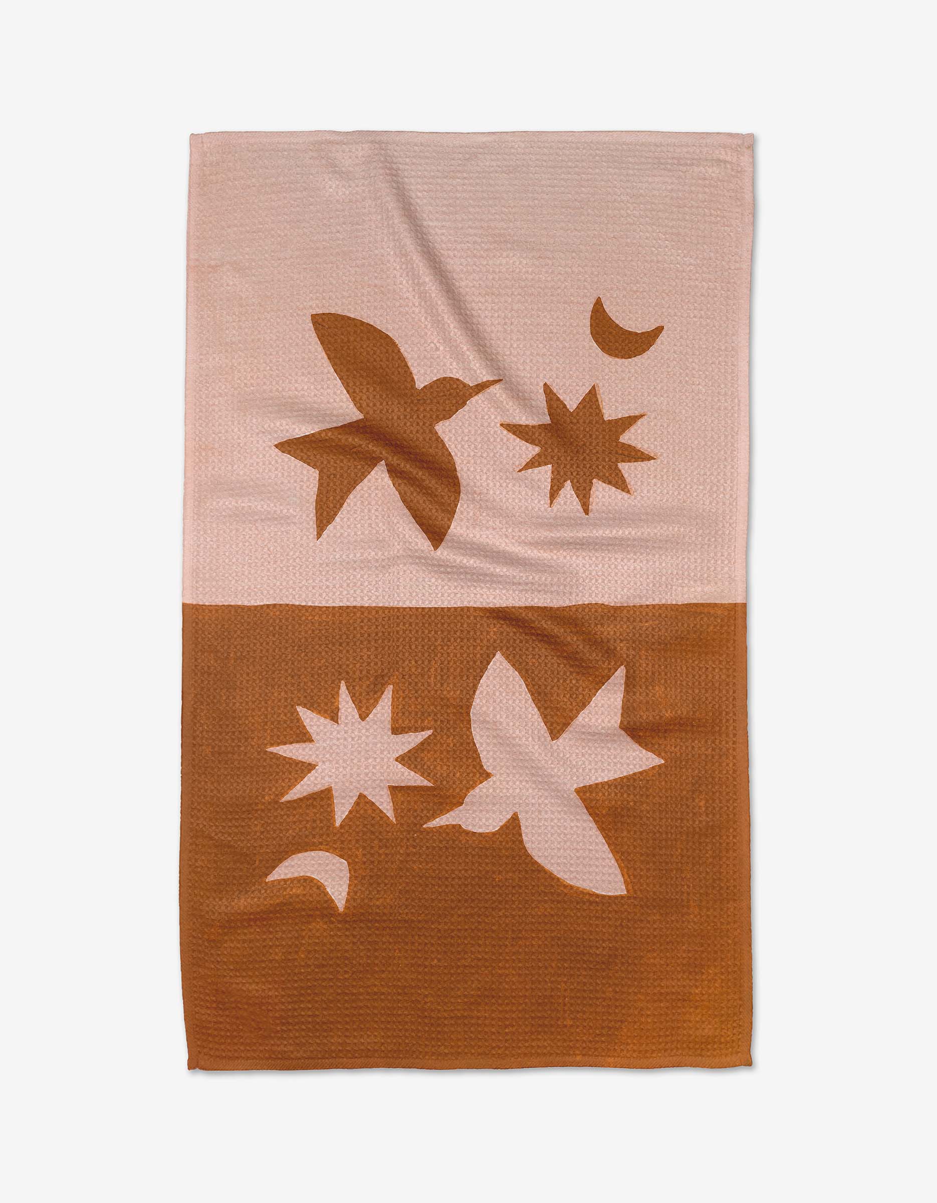 The Duality woven blanket by Jen B. Peters features abstract birds, stars, and crescent moons in light pink and rust brown, with inverted designs on each half for a modern tea towel-inspired look.