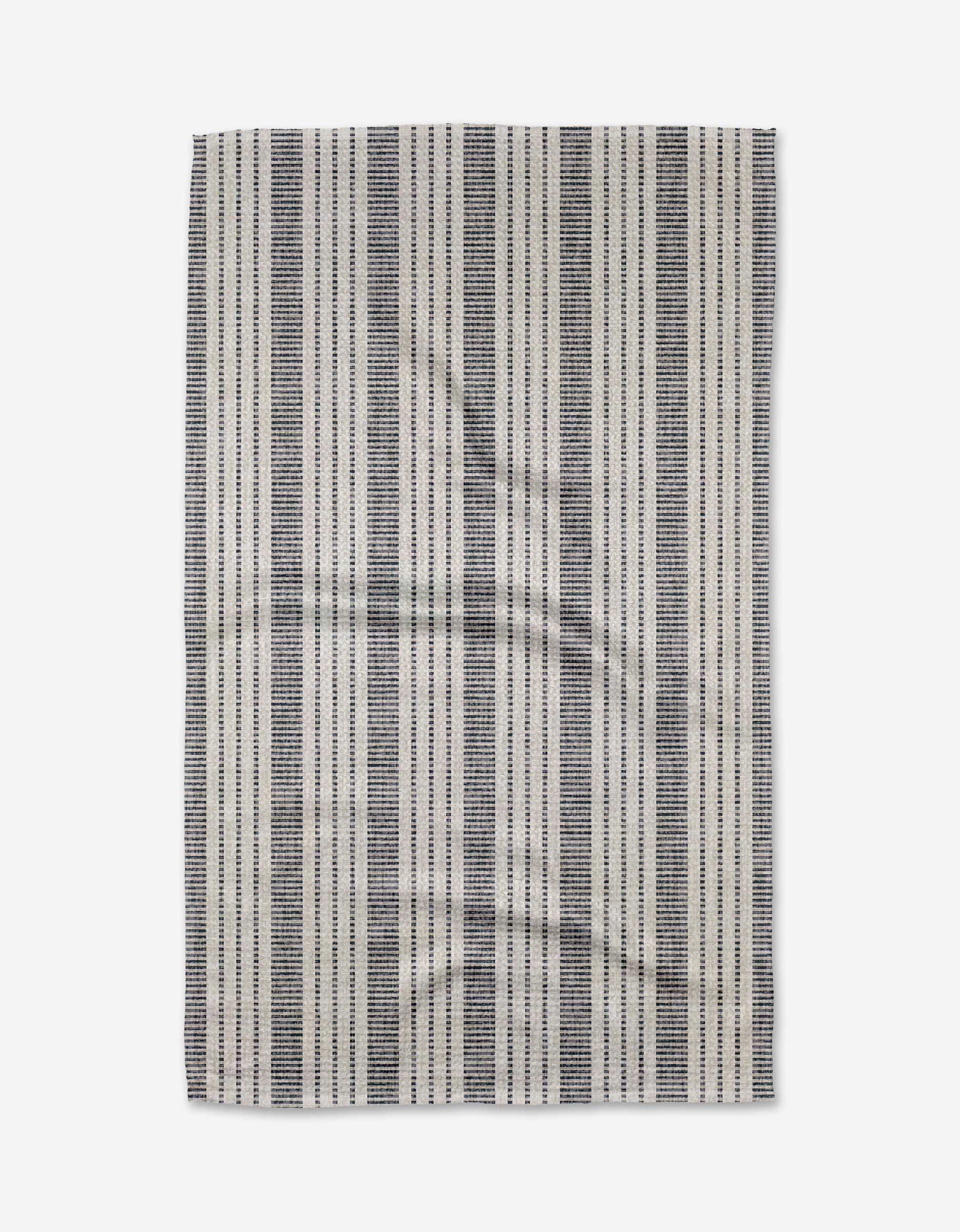 The Becki Owens Dyer Blue rug is rectangular, made from recycled materials, and showcases evenly spaced vertical black and white stripes on a light background. The rug appears slightly wrinkled and is photographed against a white surface.
