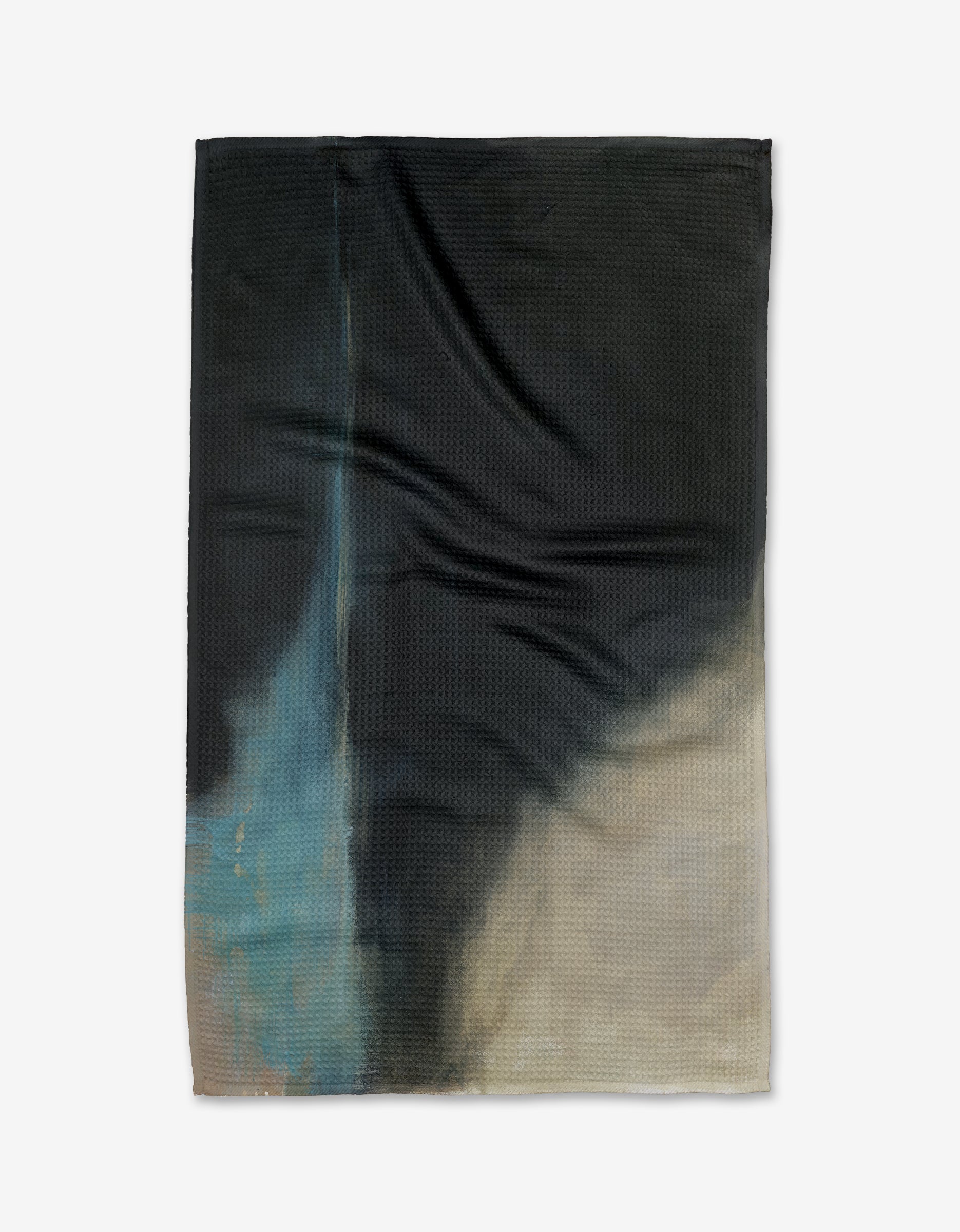 The Earth Erupted tea towel by Jennifer Janesko is a textured rectangular design made from recycled materials, showcasing an abstract gradient of dark blue, black, and beige with a lighter blue streak and soft color transitions.