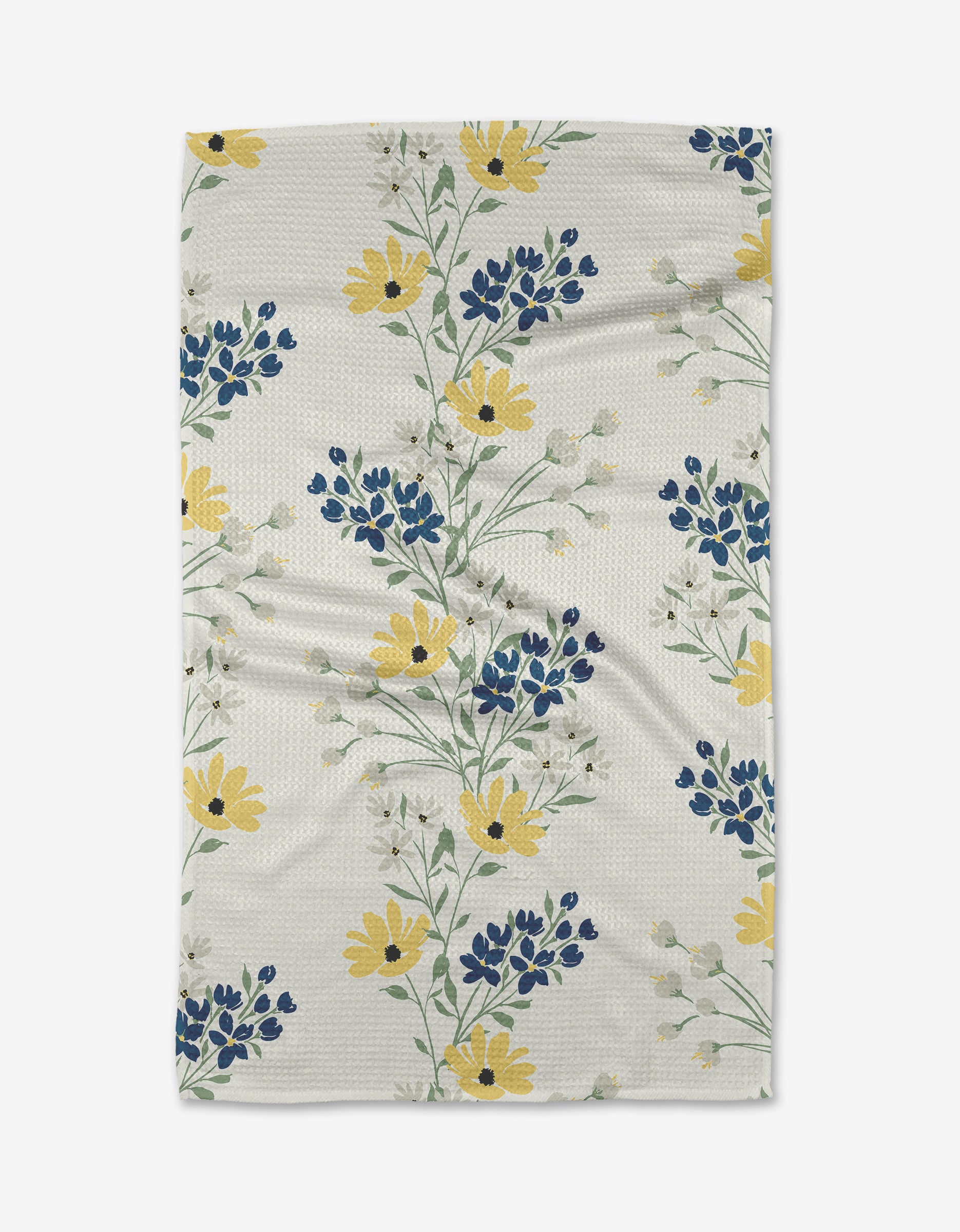 The Ashley Celena Garden Picks is a white textured blanket made from recycled materials, decorated with yellow, blue, and white floral patterns and green stems arranged diagonally on the fabric.