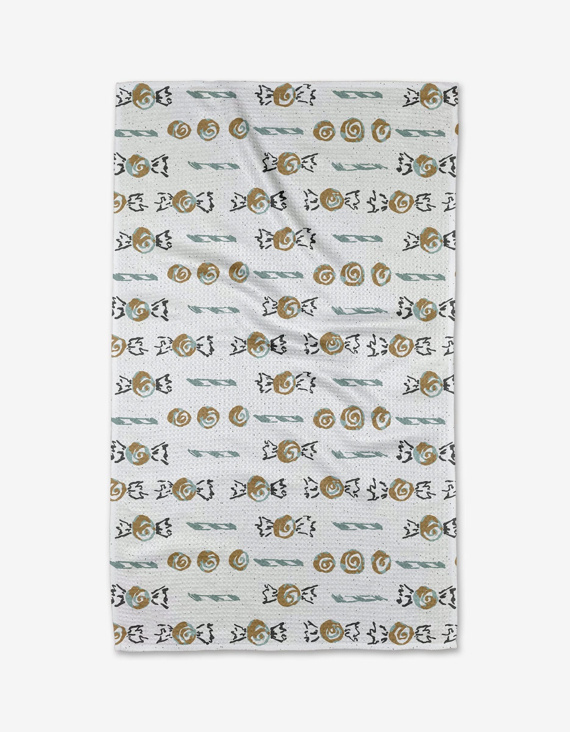 The Holiday Sweets tea towel by Toboggan Avenue is a rectangular white towel with rows of abstract brown spirals, green lines, and black shapes—crafted from recycled materials for a stylish, sustainable touch.