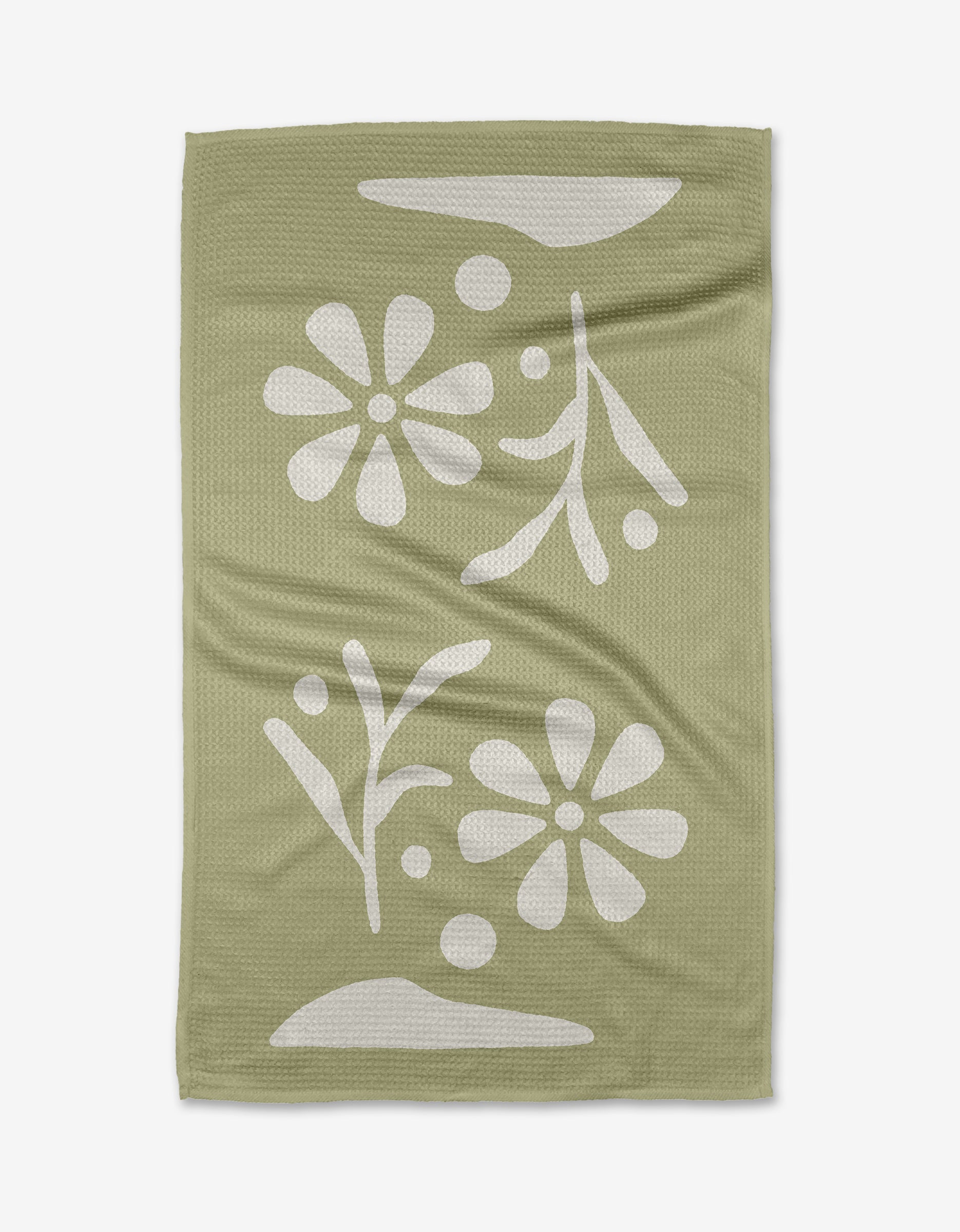 The Honey Dew tea towel by Graphics and Grain features a sage green, textured surface with a white floral and leaf pattern, abstract shapes, and dots. Made from quick-drying recycled materials.