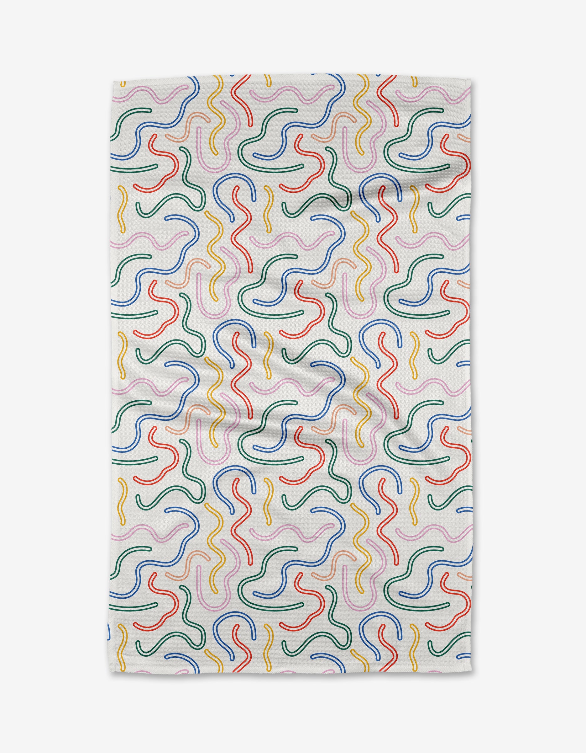 The In the Moment kitchen towel by Happy Hemera features a white fabric with wavy, multicolored squiggle patterns in red, yellow, green, and blue. Subtle creases are visible across the surface.
