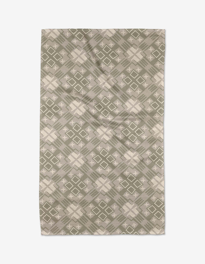 The Ash Cascade Kaleidoscope rug features a symmetrical geometric design with green and beige diamond and cross shapes, crafted from ultra-absorbent Geoweave™ fabric for kitchen tea towel-like durability.