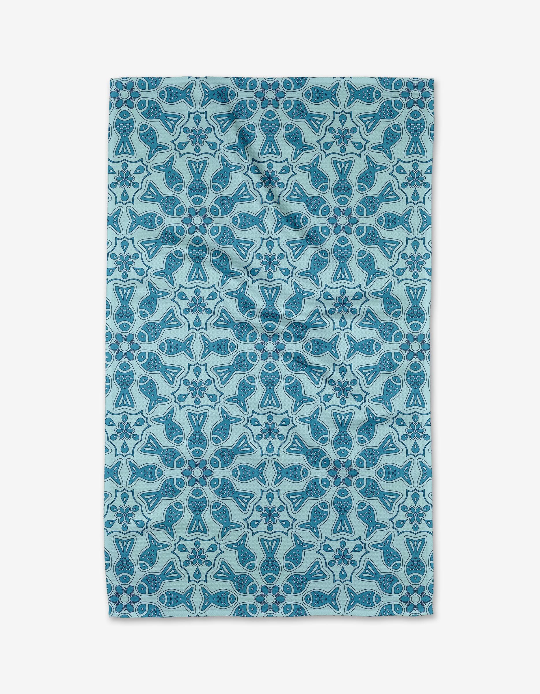 The Marta Harvey Little Fish Mandala tea towel features light blue Geoweave fabric with a symmetrical mandala of abstract fish and geometric shapes in darker blue and teal, arranged in rows and columns.