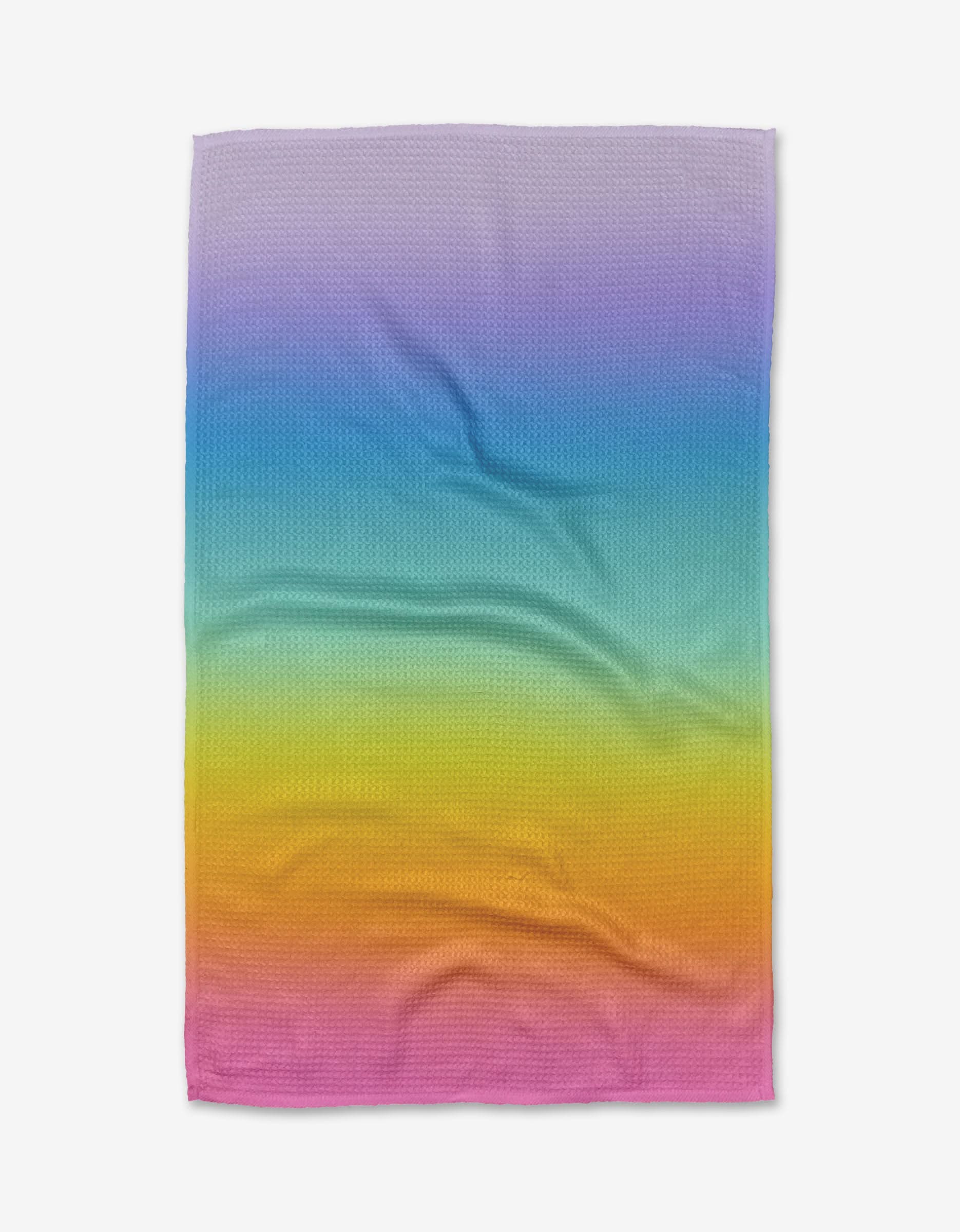 The Mac Joy towel by Noras Macarons is a rectangular, ultra-absorbent Geoweave™ fabric towel featuring a purple-to-pink gradient pattern, displayed slightly wrinkled on a white background.