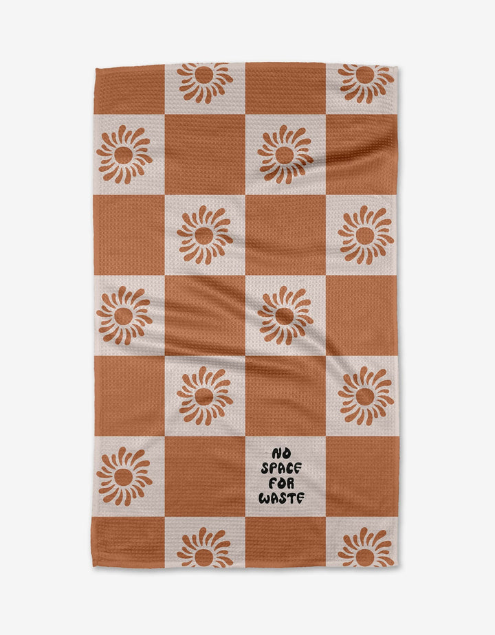 The Realm Refillery Checker by Realm Refillery is a checkered tea towel with rusty brown and white squares, sunflower accents, and NO SPACE FOR WASTE on one white square, all crafted from recycled materials.