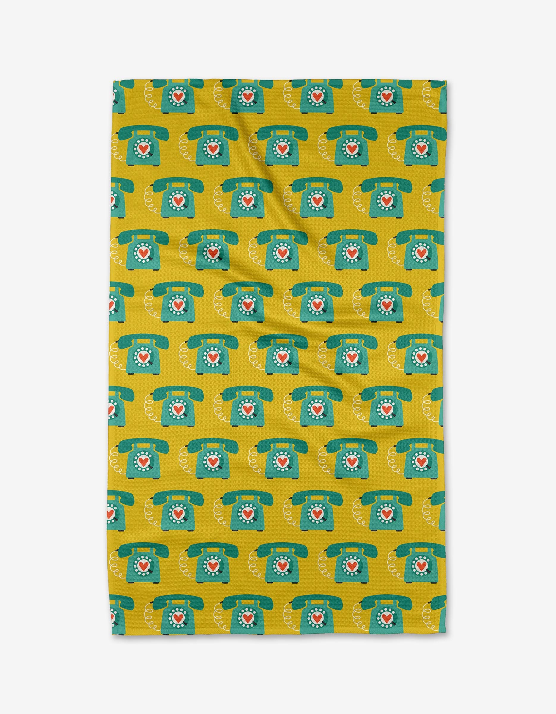 The Rotary Phones tea towel by Megan Kampa is rectangular, yellow, and made from recycled materials, featuring a green retro rotary telephone pattern with red centers. The towel is shown flat on a white background.