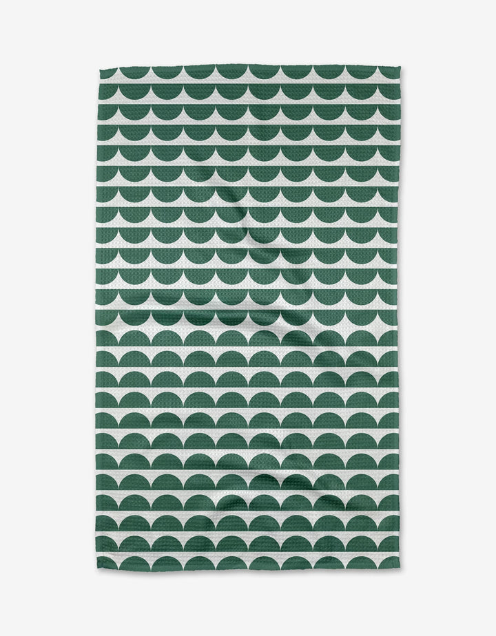 The Buy Guides Scallops - Evergreen Tea Towel displays dark green and white semi-circles on white, crafted from post-consumer recycled materials. Its eco-friendly, scalloped design is featured as it lies flat.