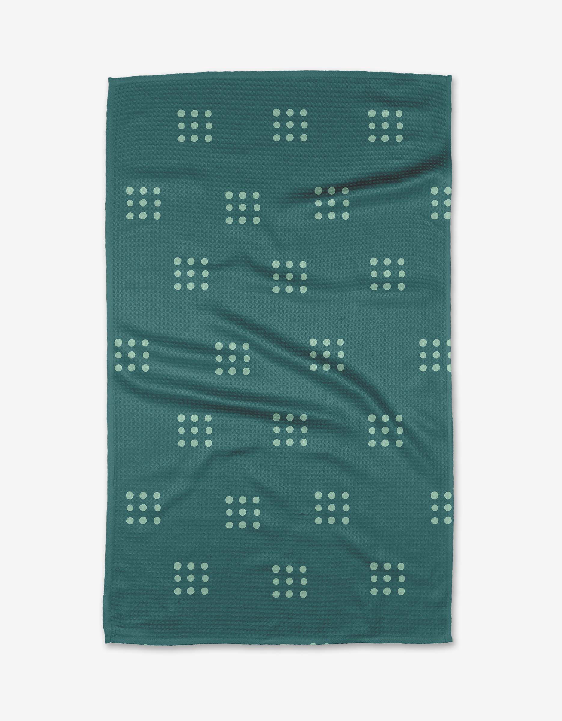 The Elizabeth Edwards Seafoam Grid towel features a dark teal rectangular design with light green grid dots, crafted from ultra-absorbent Geoweave fabric. Slight surface wrinkles are visible against the white background.