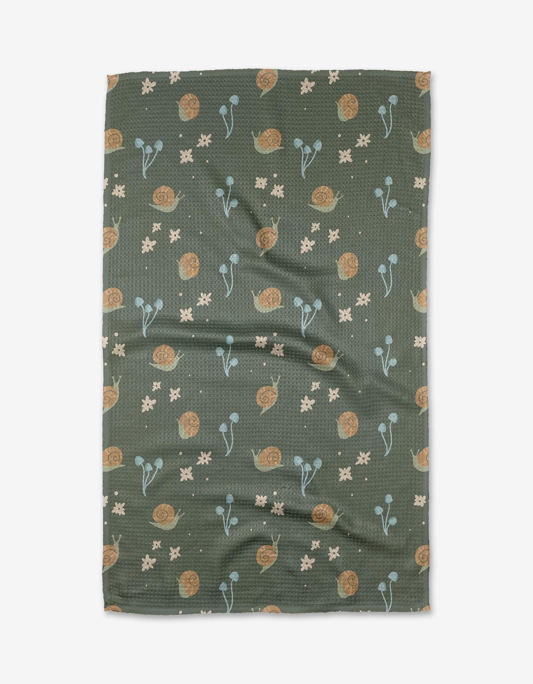 The Snail Gathering tea towel by Amberleigh Adoff is green and textured, made from recycled materials, and features brown snails, blue plants, and cream flowers. Shown flat with subtle wrinkles on a white background.