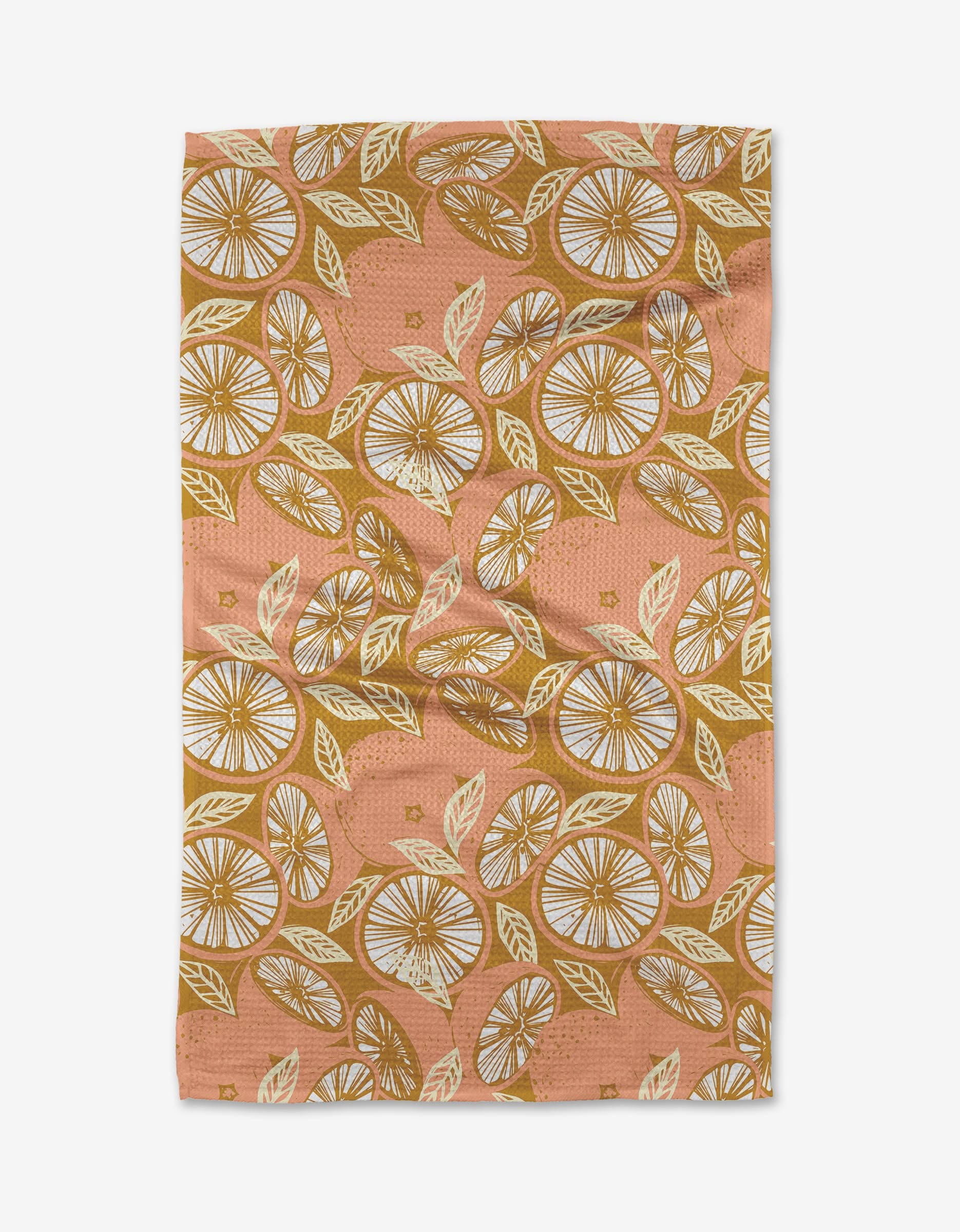 The Elisabeth Wing Spanish Grapefruit tea towel is eco-friendly in peach, adorned with a repeating citrus and leaf pattern in yellow, white, and brown tones, shown flat with gentle wrinkles.