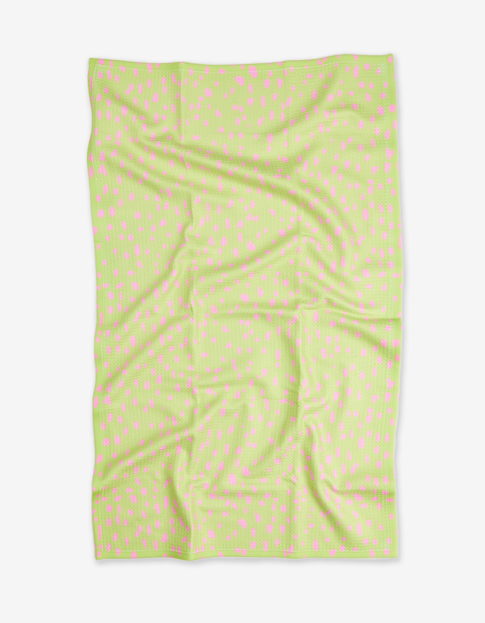 The Speckle Green blanket by GEOMETRY features a light green color with small, scattered pink dots. Made from recycled materials, it is shown flat with visible folds and creases on a white background.
