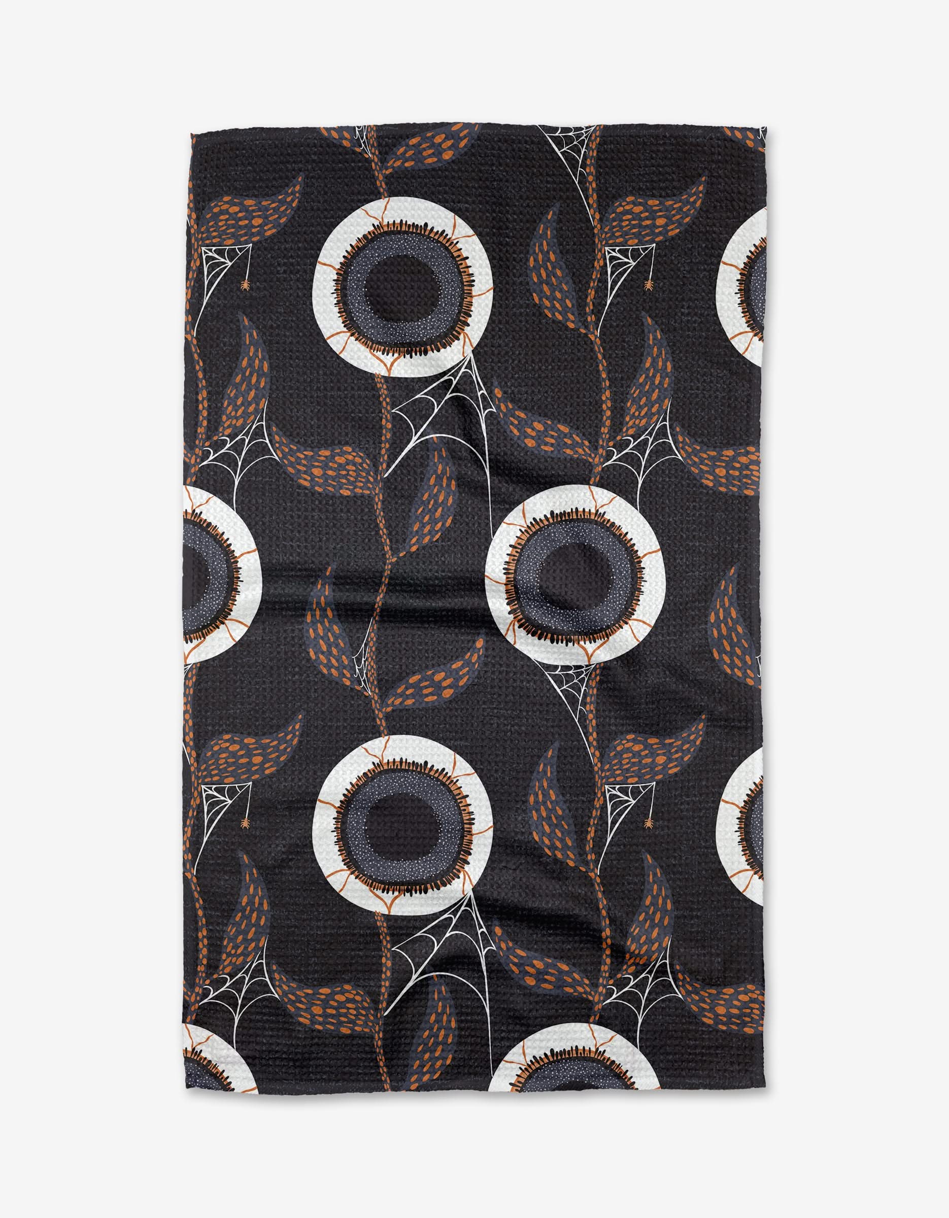 The Spider Eyes tea towel by Julianne Haness is ultra-absorbent and eco-friendly, featuring large black and white circular flowers, brown leaves, and white spiderwebs on textured recycled fabric in earthy tones.