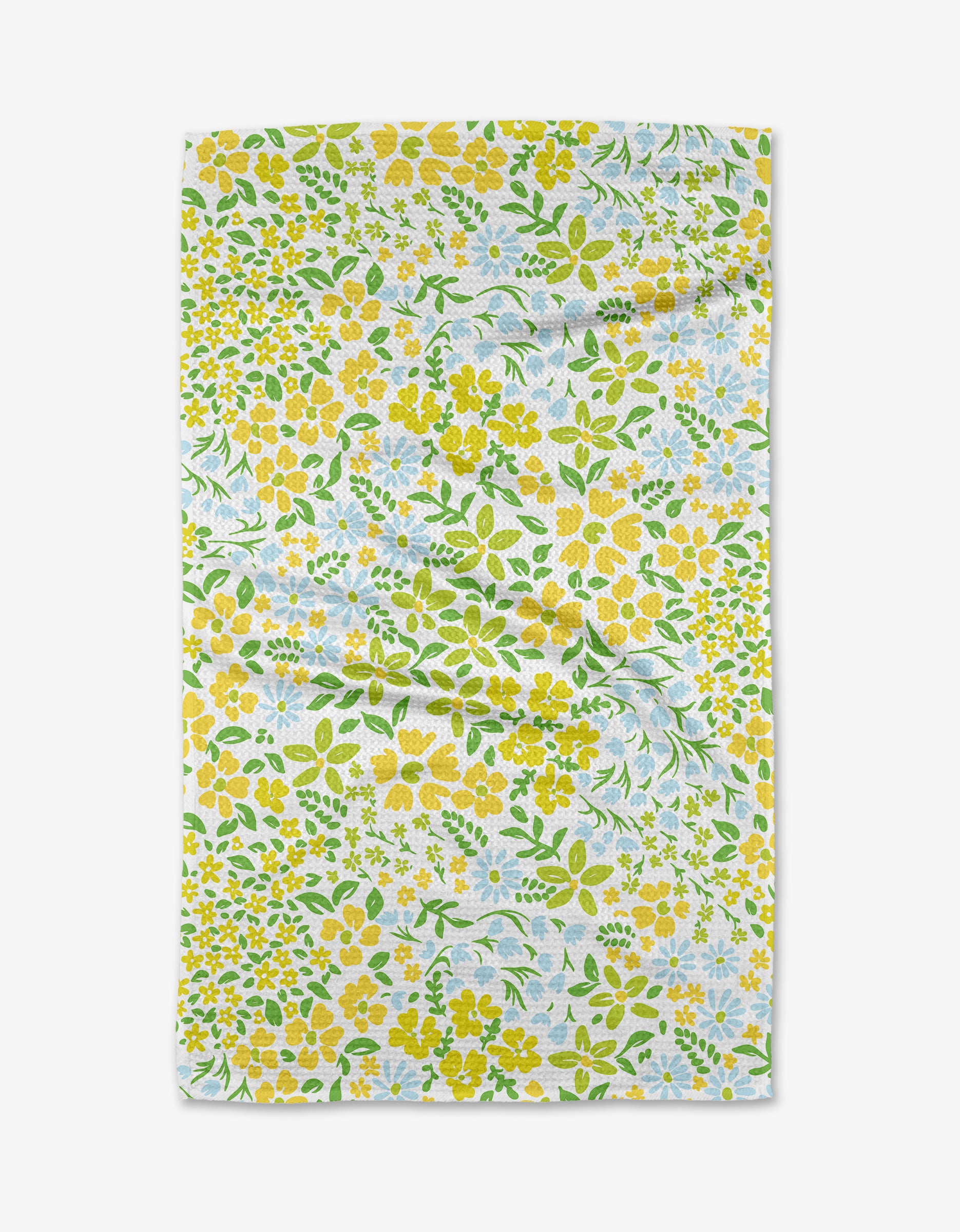 The Dabney Lee Spring Awakening tea towel features a rectangular Geoweave fabric with a floral pattern of yellow flowers, white blossoms, and green leaves on white. Its slightly wrinkled look is shown against a light backdrop.