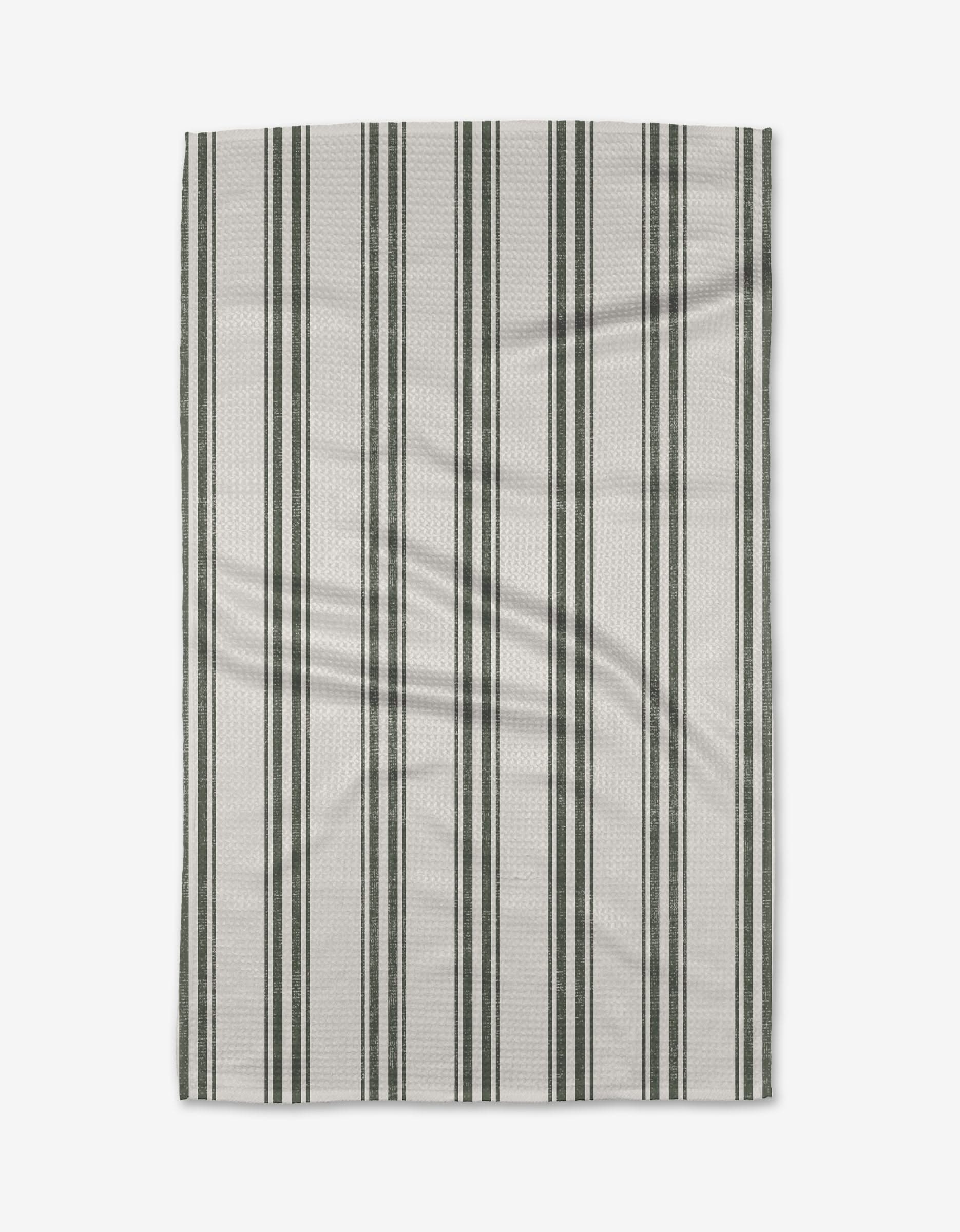 The Becki Owens Spruce tea towel is rectangular, white, and eco-friendly, with evenly spaced vertical dark green and light gray stripes—perfect for everyday kitchen use. Shown flat on a plain white background.