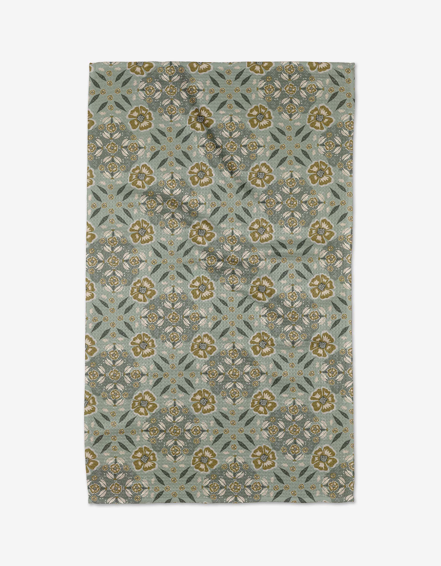 The Summit Check tea towel by Ash Cascade features a rectangular design with intricate floral and geometric patterns in olive green, gold, and gray on a muted blue-gray background, bringing charm and absorbency to any kitchen.