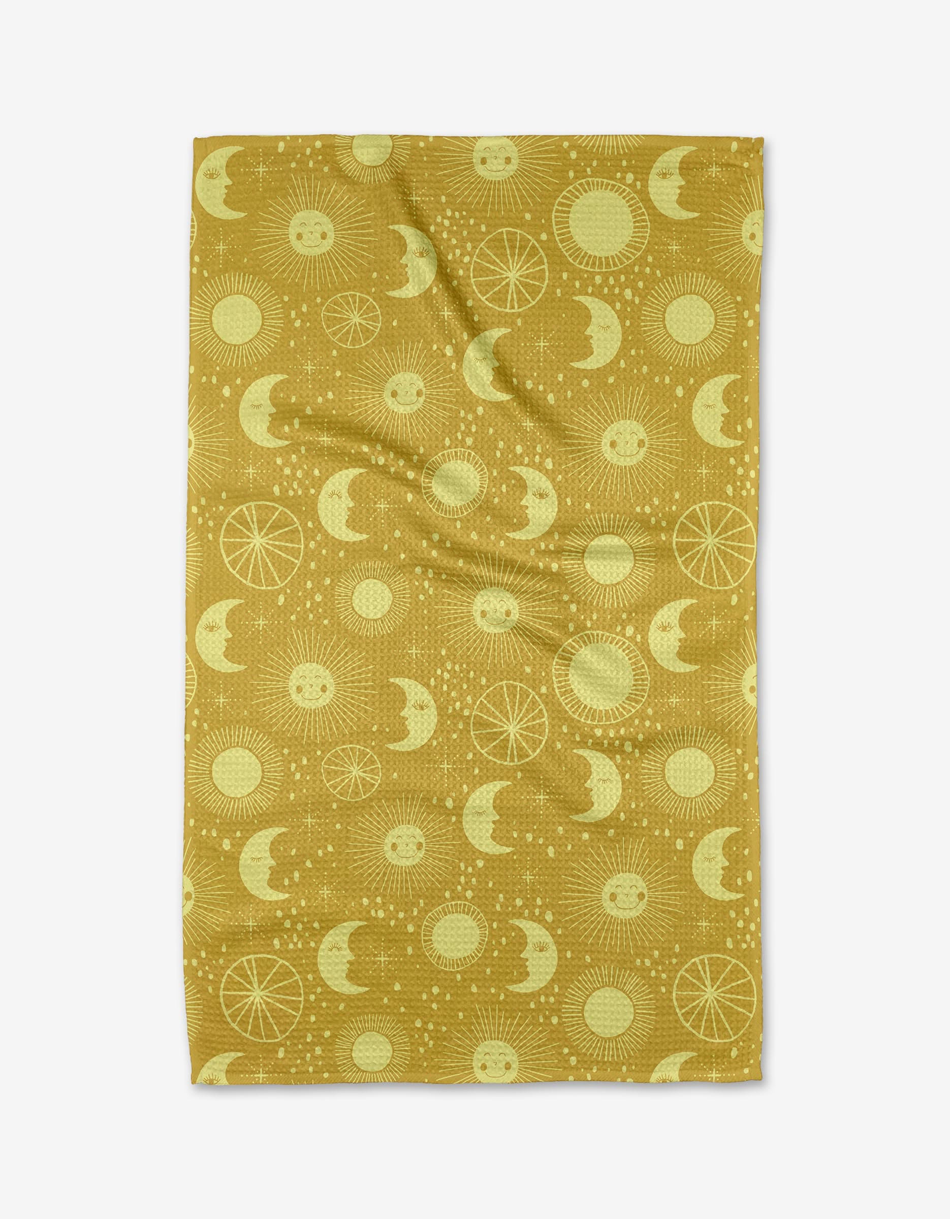 Jessica Swift’s Sun Moon Star blanket in mustard yellow features repeating suns, moons, stars, and geometric circles in lighter yellow. Shown laid flat with gentle wrinkles. Eco-friendly design.