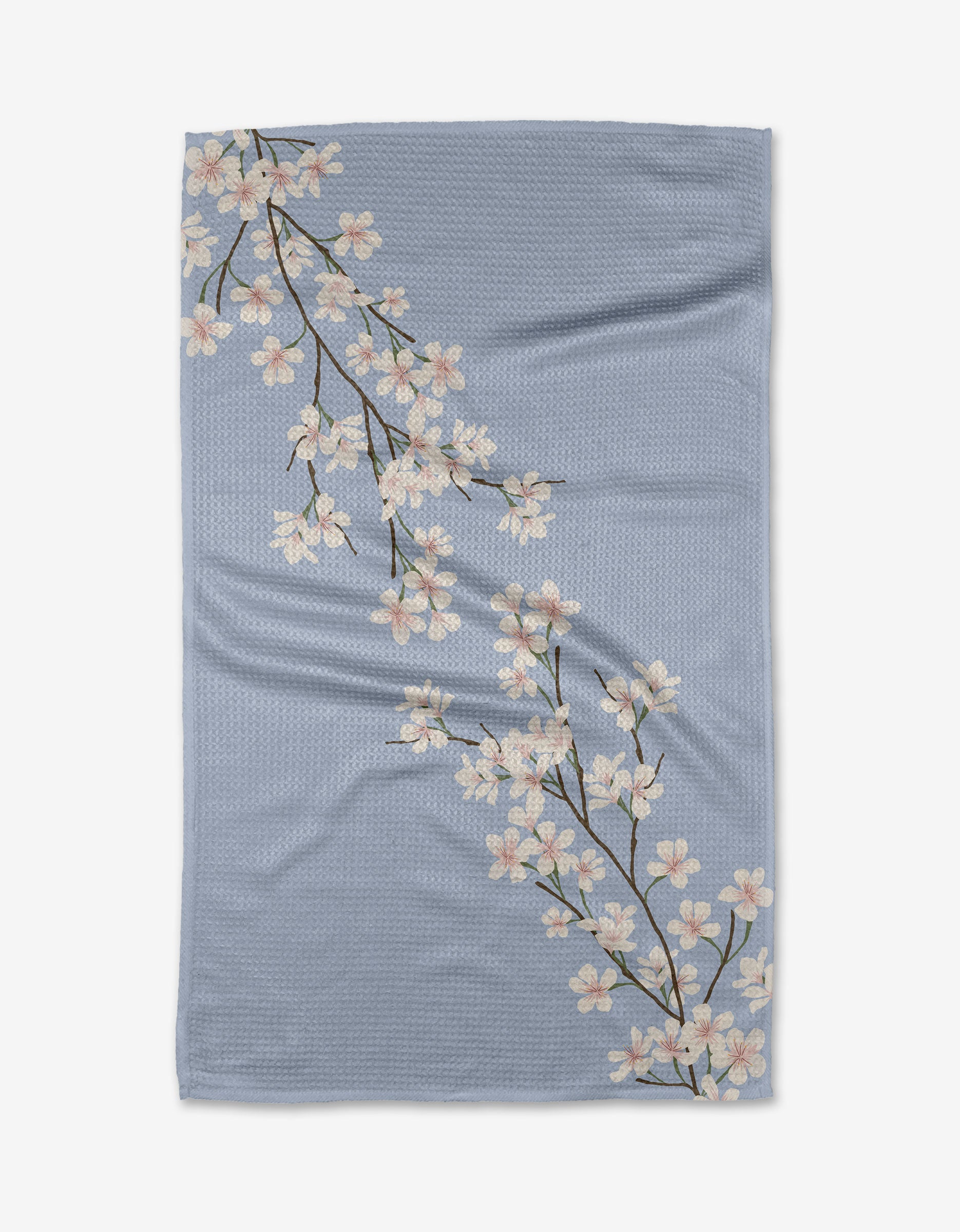 The Eve by Becki Owens is a light blue Geoweave™ blanket with two white cherry blossom branches, green leaves, and brown stems, crafted from recycled materials.