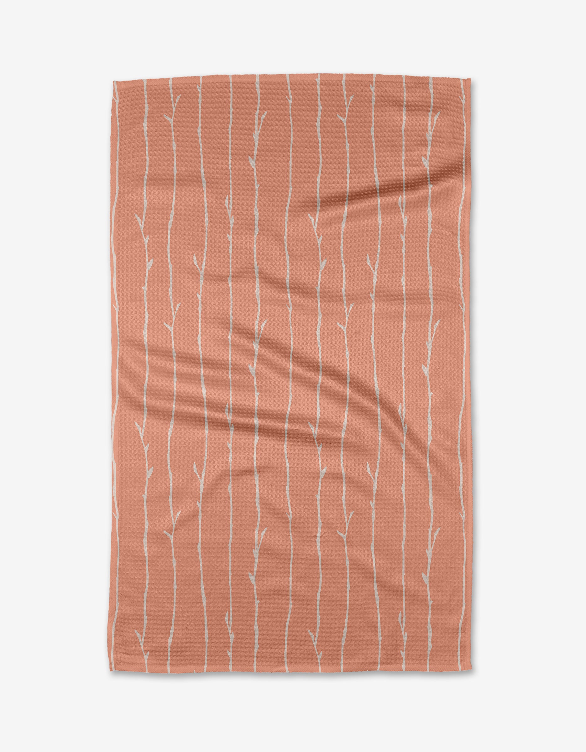 The Towering Twigs tea towel by Twig + Spark is a rectangular, soft-textured orange towel featuring a subtle white tree branch pattern, crafted from Geoweave™ fabric and shown flat on a white background.