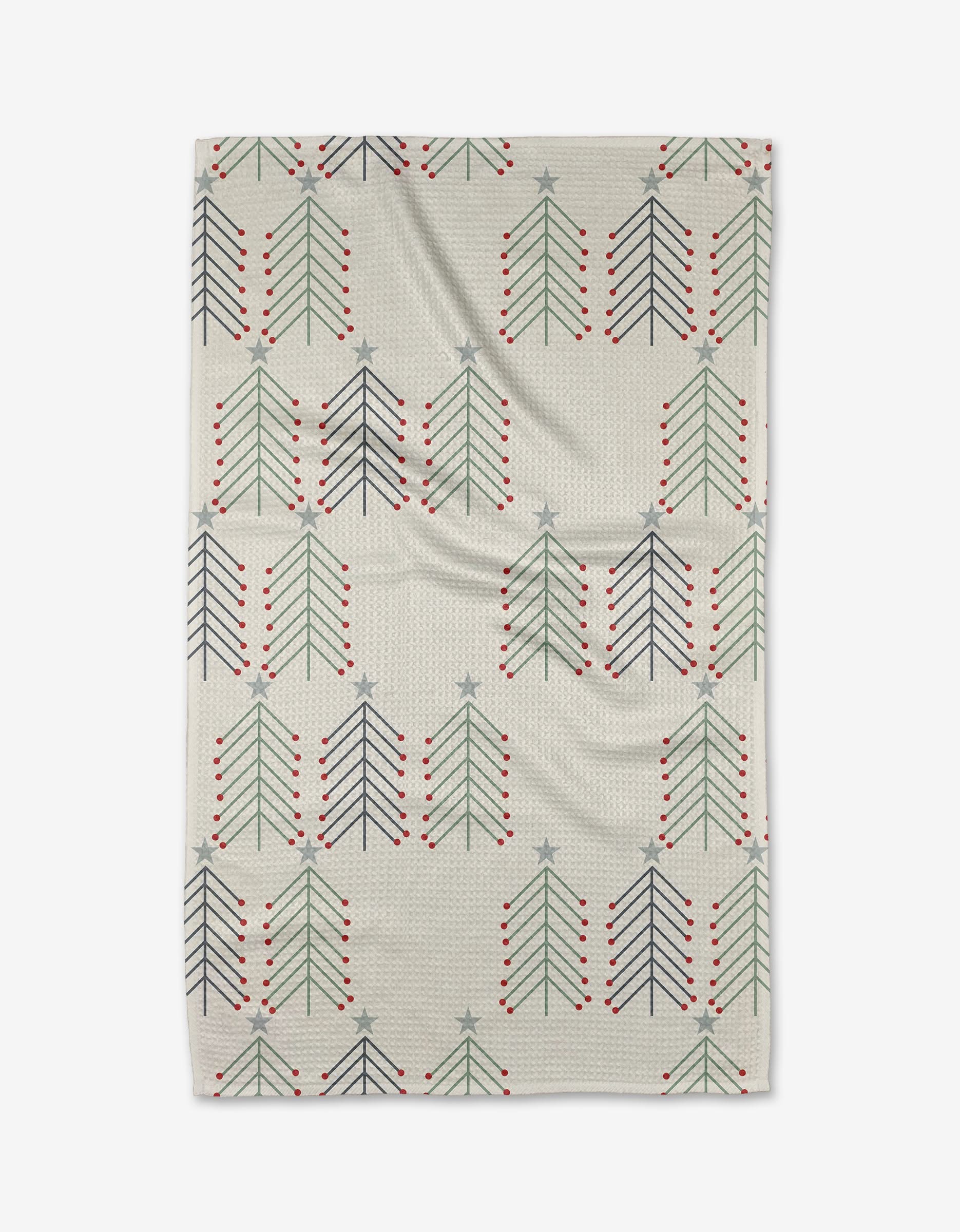 The Winter Forest blanket by Lizzie Clark is beige, made from recycled materials, and features a repeating pattern of simple Christmas trees in dark green, navy, and gray—each topped with a star and red ornaments.