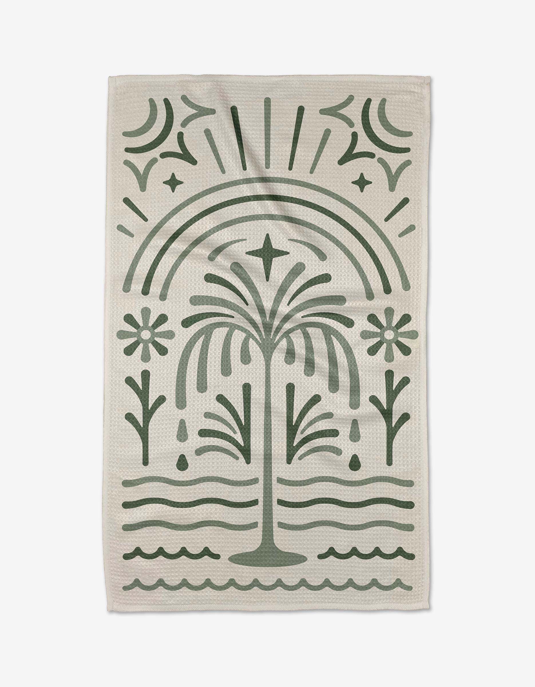 The Solana tea towel by Adam Nienow features a stylized green palm tree, flowers, waves, and an arch on beige. Made from quick-drying recycled materials for eco-friendly style.