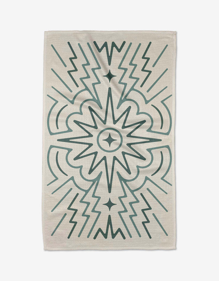 The Sunburst rug by Adam Nienow is rectangular with a cream background and symmetrical dark green geometric patterns—zigzags, arrows, and a central starburst—crafted from recycled materials.
